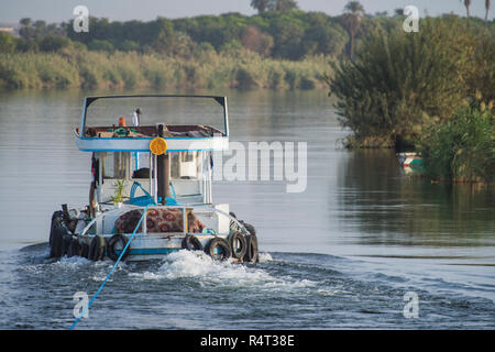 Petit remorqueur de remorquage d'un yacht de luxe sur le Nil en Egypte par le biais d'espace rural landscape Banque D'Images