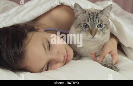 Happy teen girl baisers et des pourparlers avec Thai cat in bed Banque D'Images