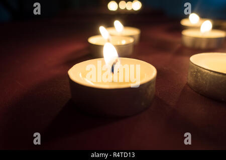 Tealight candles burning les flammes éclairant faiblement la région. Banque D'Images