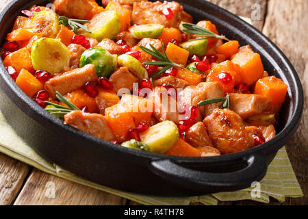 Les aliments biologiques les morceaux de poulet et légumes en sauce grenade romarin close-up dans une poêle sur la table. Banque D'Images