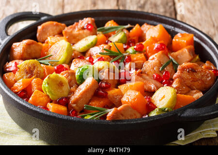 Le poulet cuit avec des légumes et romarin en sauce grenade close-up dans une poêle sur la table horizontale. Banque D'Images