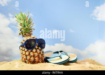 Fruit d'ananas avec des lunettes de soleil et flip flop sandals sur la plage contre un ciel bleu avec des nuages, de concept, l'espace de copie sélectionné, Banque D'Images