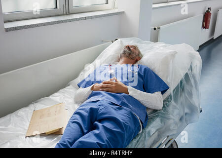 Épuisé, de repos médecin dormir sur civière in hospital corridor Banque D'Images