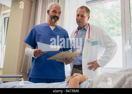 Les médecins hommes les rondes in hospital room Banque D'Images