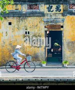 Hoi An une dame vietnamienne des thèmes d'une bicyclette dans la vieille ville UNESCO de Hoi An au Vietnam. Banque D'Images