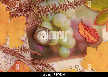 La nostalgie. Un vintage montre de poche avec les feuilles d'automne et des cartes postales anciennes, tourné par le haut, l'image aux couleurs Banque D'Images