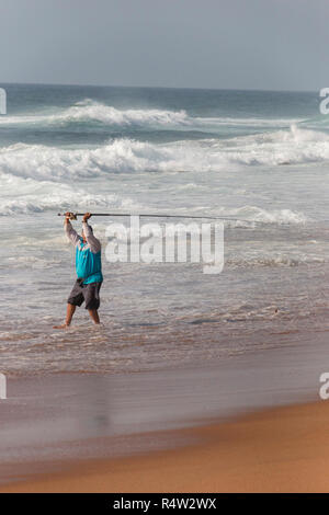 Une vue rapprochée de la face d'un fisherman casting sa rode sur la rive sur une belle journée d'été ensoleillée sur une plage de Durban Banque D'Images