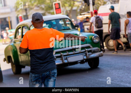 Cuban man raising hand appelant un taxi collectif dans la vieille Havane. Jeune homme Afro Cuban saluant un taxi partagé traditionnels dans la rue. Banque D'Images