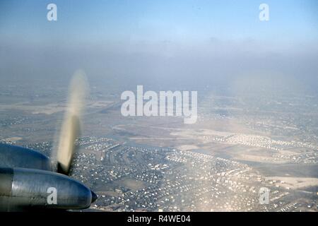 Vue aérienne vers le nord-ouest des quartiers de Woodmere, Parc Woodmere, Saddle Ridge, North Woodmere, et Valley Stream, dans la zone de cinq villes du comté de Nassau, Long Island, New York, mars 1959. En bas à gauche est le moteur à hélice d'un avion de Swissair DC 7C à l'approche de l'Aéroport International de New York Idlewild juste hors du cadre. Visible en bas à l'arrière-plan au-delà du nez du moteur est le bâtiment de l'école Académie Woodmere Saint-laurent au milieu d'une clairière herbeuse entourée par l'habitat résidentiel. Juste au-dessus en diagonale au bord inférieur de la péninsule est Bou Banque D'Images