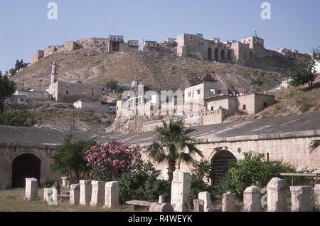 Vue sur le flanc de la maison autour de la forteresse médiévale de Qalaat Al-Madiq, Syrie, Juin, 1994. Au premier plan est la cour de l'époque ottomane à l'extérieur de l'Apamée musée archéologique, à côté de l'ancienne cité romaine ruines d'Apamée. () Banque D'Images