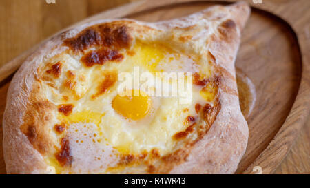 Ouvrez adjare khachapuri avec du fromage et des oeufs sur planche de bois. L'alimentation du Caucase traditionnels Banque D'Images