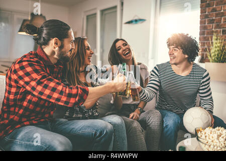 Les amis sont des fans de jeux de sport le football aime passer leur temps libre ensemble, à la maison. Ils crient et gesticulant pour une victoire. Banque D'Images