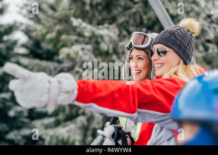 Belle jeune femme bénéficiant d'amis en vacances d'hiver. Ils la conduite sur la remontée mécanique et à l'écart avec sourire. Banque D'Images