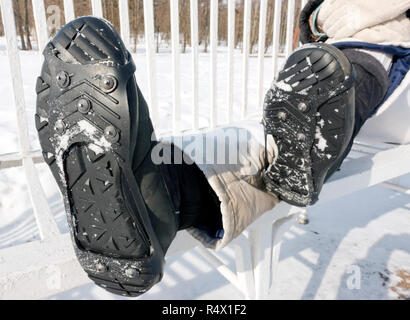 Sur la garniture avec des crampons pour marcher sur la glace, les routes glissantes en hiver. Les jambes des femmes close up et empreinte sur la neige Banque D'Images