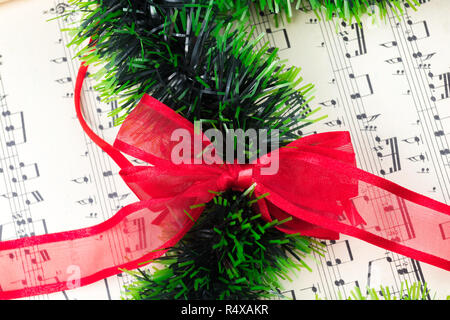 Ornement de Noël et musique sur feuille naturel blanc table en bois. Red Ribbon bow. Banque D'Images