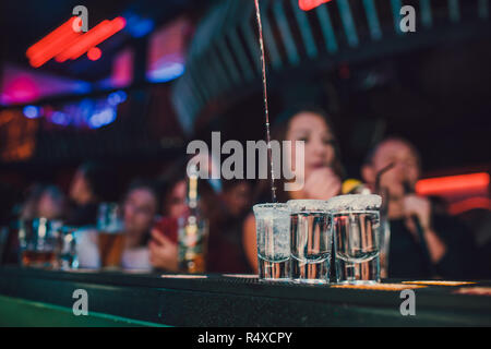 Apéritif entre amis dans le bar, cinq verres d'alcool avec des collations et de lime pistache, sel et piments rouges pour la décoration. Des coups de Tequila, vodka, whisky, rhum. focus sélectif et copiez l'espace. Banque D'Images