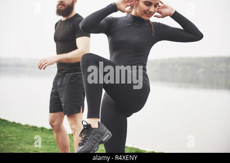 Un jeune couple aime jouer au sport dans la matinée à l'air libre. Réchauffer avant l'exercice Banque D'Images