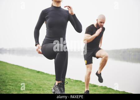 Un jeune couple aime jouer au sport dans la matinée à l'air libre. Réchauffer avant l'exercice Banque D'Images