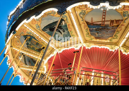 Un vieux Carrousel, peint avec des scènes de la vie de San Francisco dans une fin de journée la lumière, Pier 39, San Francisco, California, USA Banque D'Images