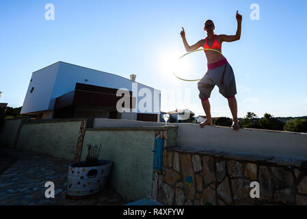 Jolie femme adulte joue avec cerceau dans la nature. Jeune, en bonne santé, active hipster femme est le hula hoop sur jardin méditerranéen avec vue sur Banque D'Images