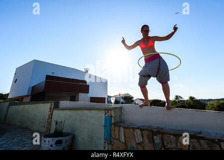 Jolie femme adulte joue avec cerceau dans la nature. Jeune, en bonne santé, active hipster femme est le hula hoop sur jardin méditerranéen avec vue sur Banque D'Images