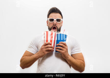 Peur et inquiétude jeune homme se dresse et tient seau de popcorn avec verre de cola. Il est frightned beaucoup. Jeune homme garde la bouche ouverte. Isolé sur fond blanc. Banque D'Images