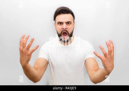 Jeune homme en colère émotionnelle et regarde la caméra. Il exprime ses émotions et montrer les mains. Isolé sur fond blanc. Banque D'Images