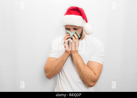 Jeune homme malade dans Red Hat et éternue en serviette. Il est malade. Guy de malheureux. Isolé sur fond blanc. Banque D'Images