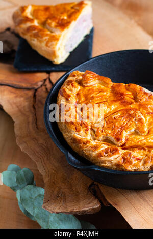 Concept alimentaire des pork pie ou pâté à la viande dans la poêle en fonte et plaque en pierre sur fond de bois Banque D'Images