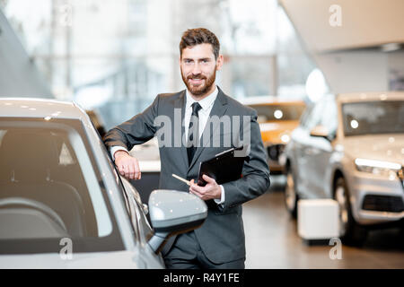 Portrait of a handsome le vendeur dans la fonction à l'extérieur de la voiture dans le showroom Banque D'Images