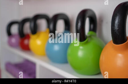 Poids multi-couleurs dans le centre de remise en forme féminine. kettlebells sont sur les étagères dans la salle de sport Banque D'Images