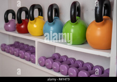 Poids multi-couleurs dans le centre de remise en forme féminine. kettlebells sont sur les étagères dans la salle de sport Banque D'Images
