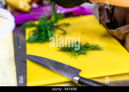 Male Chef Cutting Dill sur jaune - Set de cuisine Banque D'Images