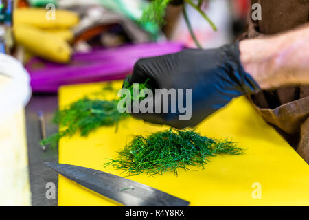 Male Chef Cutting Dill sur jaune - Set de cuisine Banque D'Images