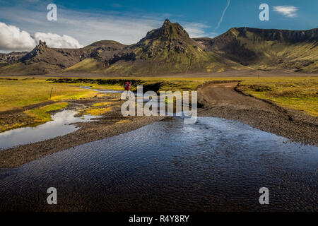 Le dirigeant d'une female hiker traverser une petite rivière sur le sentier Laugavegur en Islande. Banque D'Images