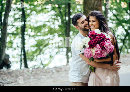 Les jeunes, l'heureux couple est marchant le long de la route dans un parc d'été. Banque D'Images