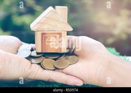Chambre placés sur les pièces de monnaie dans la main des hommes est l'épargne de l'argent planification de pièces de monnaie pour acheter une maison concept concept pour l'accession à la propriété, des prêts hypothécaires et l'immobilier investir Banque D'Images