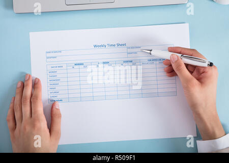 Businesswoman remplissant la feuille de temps hebdomadaire Banque D'Images