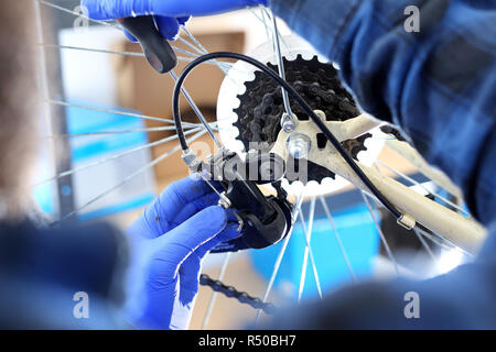 L'homme se resserre et lubrifie du dérailleur dans le vélo militaire. l'homme répare le vélo. réparation de vélos bike service,réparation de vélos Banque D'Images