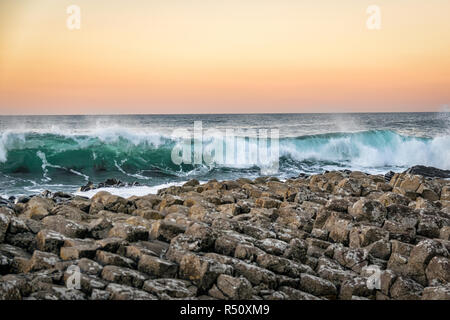 Cette photo a été prise au coucher du soleil. Il est d'une vague de frapper la Chaussée des Géants en Irlande du Nord.