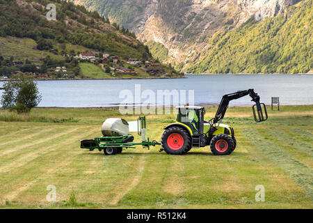 Petit tracteur avec une balle ronde pack sur un champ à Geiranger, Norvège. Banque D'Images