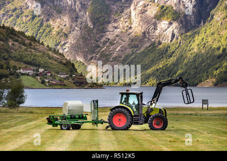 Petit tracteur avec une balle ronde pack sur un champ à Geiranger, Norvège. Banque D'Images