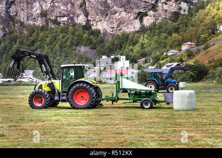 Petit tracteur avec une balle ronde pack sur un champ à Geiranger, Norvège. Banque D'Images