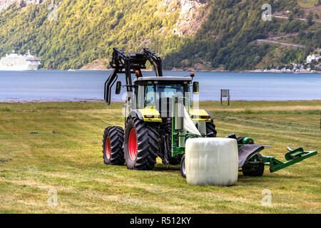 Petit tracteur avec une balle ronde pack sur un champ à Geiranger, Norvège. Banque D'Images