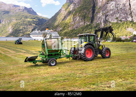 Petit tracteur avec une balle ronde pack sur un champ à Geiranger, Norvège. Banque D'Images