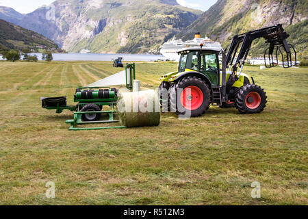 Petit tracteur avec une balle ronde pack sur un champ à Geiranger, Norvège. Banque D'Images