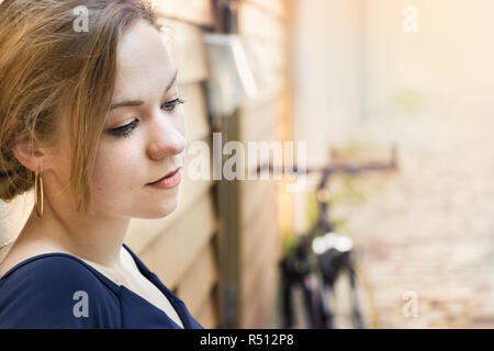 Portrait of blond woman, pensive, rêvant d'une façon nostalgique, à l'extérieur. Banque D'Images