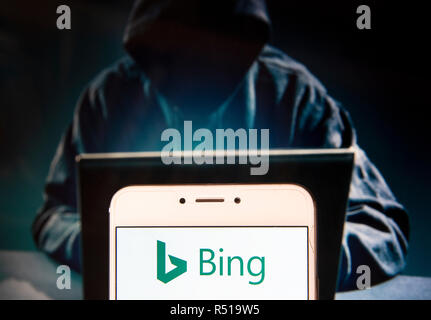 Moteur de recherche appartenant à Microsoft, Bing, le logo est vu sur un appareil mobile Android avec une figure de hacker dans l'arrière-plan. Banque D'Images