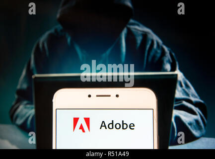Multimedia informatique multinationale américaine et la créativité software logo de l'entreprise est vu sur un appareil mobile Android avec une figure de hacker dans l'arrière-plan. Banque D'Images