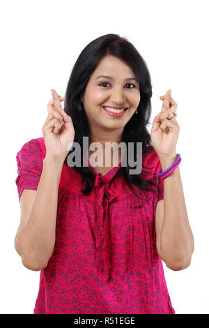 Jeune femme heureuse crossing fingers against white Banque D'Images